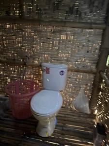 a bathroom with a toilet and a basket at Cat Hut Farmstay in Ban Khok Yom
