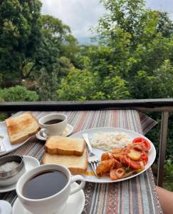 a table with a plate of food and two cups of coffee at Hotel PeaceFul in Bandipur