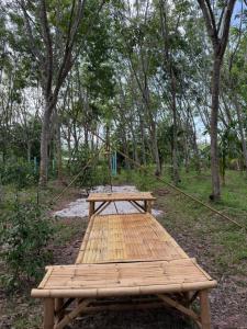 a wooden picnic table in a forest with trees at Cat Hut Farmstay in Ban Khok Yom