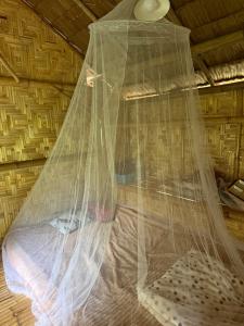 a bed covered in mosquito net in a room at Cat Hut Farmstay in Ban Khok Yom
