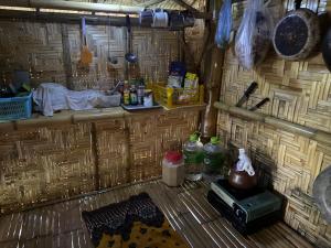 a room with a wooden wall with a table and bottles at Cat Hut Farmstay in Ban Khok Yom