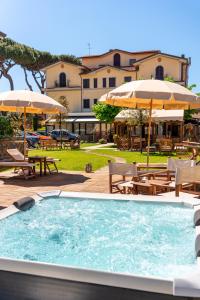 a swimming pool with umbrellas and tables and chairs at Hotel Virginia in Marina di Massa