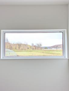 a window in a white wall with a view of a field at cottage hapo in Higashikagura +1 photo