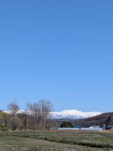 a field with snow covered mountains in the background at cottage hapo in Higashikagura
