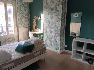 a bedroom with green walls and a bed with pillows at Au coeur d'Harfleur in Harfleur