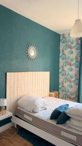 a bedroom with a large bed with a blue wall at Au coeur d'Harfleur in Harfleur
