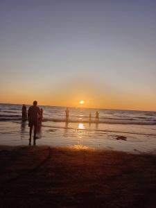 a group of people walking on the beach at sunset at The Alibag Beach hotel- Grantley in Alībāg
