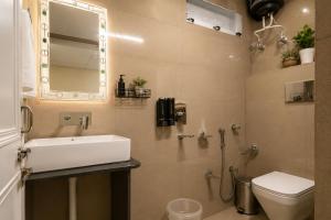 a bathroom with a sink and a toilet and a mirror at Bir Haus in Bīr