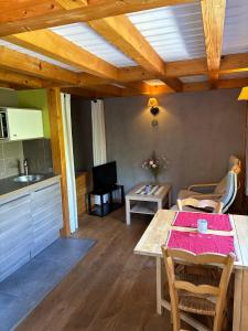 a living room with a table and a kitchen at Omazot au calme dans verdure in Aix-les-Bains