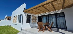 a patio with two chairs and a table on a house at Sage & Salt in St. Helena Bay