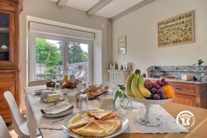 a dining room table with a bowl of fruit and bread at Le clos des sittelles in Theix