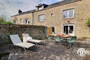 a patio with a table and chairs in front of a brick building at Le clos des sittelles in Theix