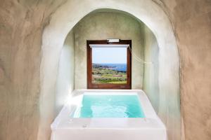 a bath tub in a room with a window at Santorini Rooftop Hot Tub Suite with Panoramic Views in Akrotiri