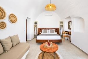 a bedroom with a bed and a couch and a table at Santorini Rooftop Hot Tub Suite with Panoramic Views in Akrotiri +25 photos