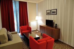 a hotel room with red chairs and a television at Corner Hotel & Kávéház in Dunaújváros