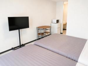 a room with two beds and a flat screen tv at MrKINJO in Air Resort in Hirara