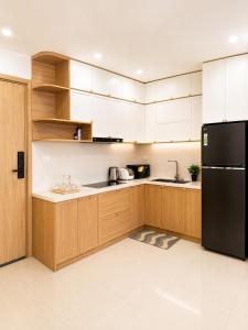 a kitchen with wooden cabinets and a black refrigerator at Nera Stay Huế - Luxury Apartment in Hue