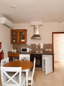 a kitchen with a wooden table and white chairs at Aparthotel Bahia Pinosol in Jávea