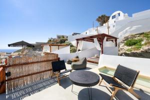 a patio with chairs and a table on a balcony at Santorini Rooftop Hot Tub Suite with Panoramic Views in Akrotiri