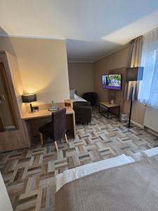 a hotel room with a desk and a bed and a television at Hotel & Restaurant Landgasthaus Zander in Blankenburg