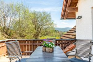 a wooden table on a deck with chairs and flowers at Fewo Enzian in Breitenberg