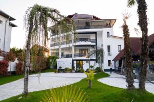 a large white building with palm trees in front of it at Denta Suport in Râmnicu Vâlcea