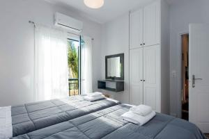 a white bedroom with a large bed and a window at Ariti Apartments in Kassiopi