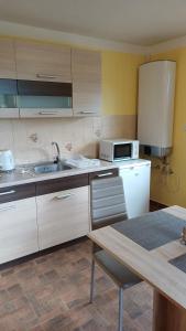 a kitchen with white cabinets and a sink and a table at Apartmány-Včelka in Trpnouze +4 photos