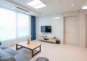 a living room with a couch and a tv at Firstcity Hotel YEOSU in Yeosu