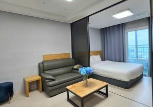 a hotel room with a couch and a bed and a table at Firstcity Hotel YEOSU in Yeosu