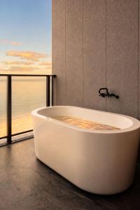 a bath tub in a bathroom with a view of the ocean at nagisa awajishima in Awaji