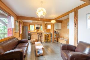 a living room with leather furniture and a kitchen at Gite Nature Ressourcement-Vosges in Le Tholy