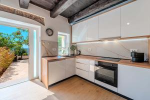 a kitchen with white cabinets and a large window at Angelina in Jakišnica
