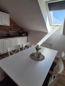 a white table in a kitchen with white chairs at Apartmán By One in Banská Štiavnica