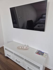 a white dresser with a tv on a wall at Apartmán By One in Banská Štiavnica