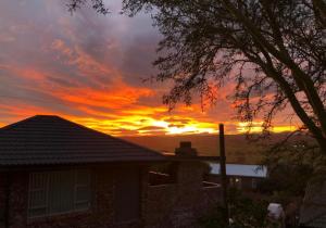 a sunset behind a house with a house at Coastal Cottage in Klein-Brakrivier +15 photos