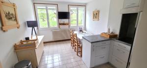 a kitchen with white cabinets and a table and chairs at MV Vacances in Les Rousses