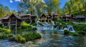 a group of wooden cabanas next to a waterfall at Apartment Baki in Jajce