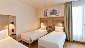 a hotel room with two beds and a window at Campanile Prime - Paris 14 Maine Montparnasse in Paris