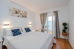 a white bedroom with a white bed and a window at Angelina in Jakišnica