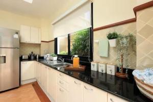 a kitchen with white cabinets and a black counter top at Laguna Fairway 3B villa-golf view in Laguna Phuket