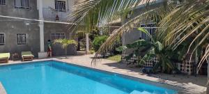 a swimming pool next to a building with a palm tree at Unique Owl Apartments in Sanyang