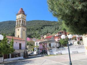 a town with a clock tower in front of a mountain at La Dimora di Basilica in Ágios Matthaíos