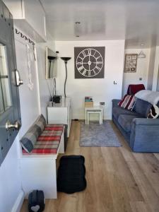 a living room with a couch and a clock on the wall at The Annexe At The Old Mill in Camborne