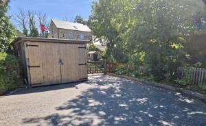 a wooden garage with a fence and a house at The Annexe At The Old Mill in Camborne +12 photos