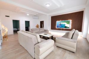 a living room with white furniture and a painting on the wall at Premium Stay Prishtina in Prishtinë