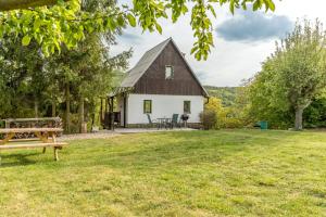 a white house with a black roof and a picnic table at Chata obklopena přírodou in Malé Žernoseky