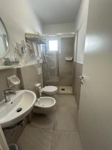 ein Badezimmer mit Waschbecken, Toilette und Dusche in der Unterkunft Hotel Soave in Cervia