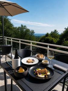 a table with plates of food and a glass of wine at Hotel SPA Restaurant Husseren Collections - Proche Colmar - Eguisheim in Eguisheim