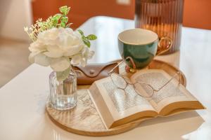 a tray with a book and a cup and a vase with glasses at Le splendide - modern & cocooning in Tarbes +21 photos